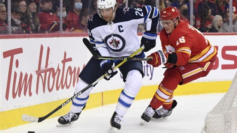 Nov 27, 2021; Calgary, Alberta, CAN; Winnipeg Jets forward Blake Wheeler (26) battles for the puck with Calgary Flames defenseman Nikita Zadorov (16) during the first period at Scotiabank Saddledome. Mandatory Credit: Candice Ward-USA TODAY Sports