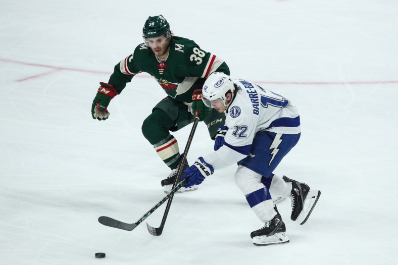 Nov 28, 2021; Saint Paul, Minnesota, USA; Tampa Bay Lightning center Alex Barr  -Boulet (12) skates with the puck while Minnesota Wild right wing Ryan Hartman (38) defends in the second period at Xcel Energy Center. Mandatory Credit: David Berding-USA TODAY Sports