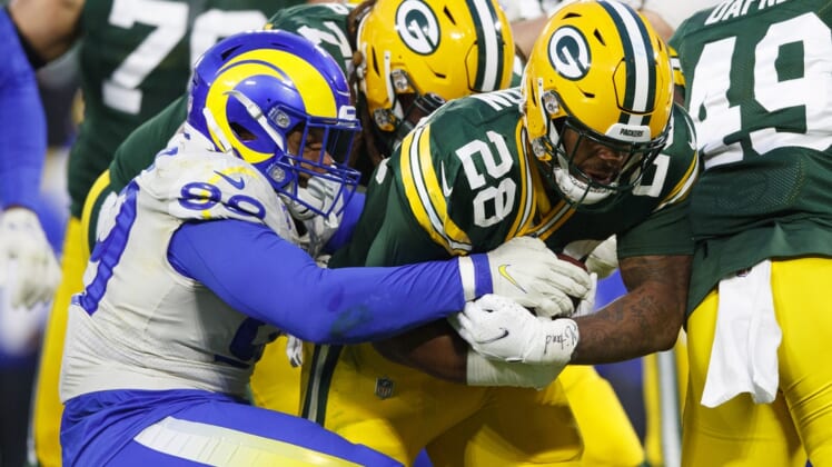 Nov 28, 2021; Green Bay, Wisconsin, USA;  Green Bay Packers running back AJ Dillon (28) is tackled by Los Angeles Rams defensive tackle Aaron Donald (99) during the second quarter at Lambeau Field. Mandatory Credit: Jeff Hanisch-USA TODAY Sports