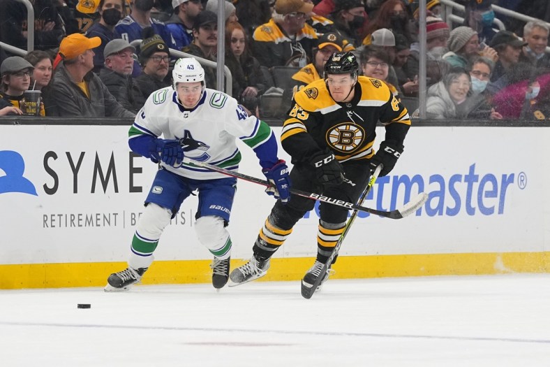 Nov 28, 2021; Boston, Massachusetts, USA; Vancouver Canucks defenseman Quinn Hughes (43) and Boston Bruins right wing Karson Kuhlman (83) chase the puck during the first period at TD Garden. Mandatory Credit: Gregory Fisher-USA TODAY Sports