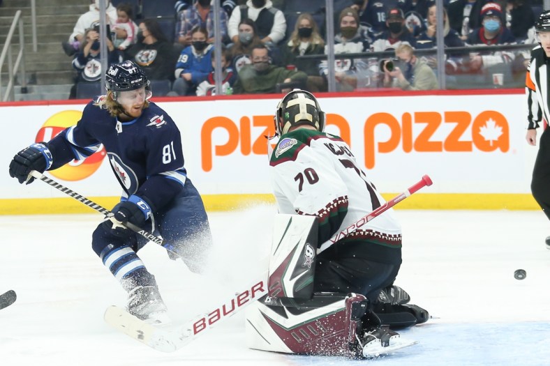Nov 29, 2021; Winnipeg, Manitoba, CAN;  Winnipeg Jets forward Kyle Connor (81) watches the puck go past Arizona Coyotes goalie Kyle Capobianco (70) during the second period at Canada Life Centre. Mandatory Credit: Terrence Lee-USA TODAY Sports