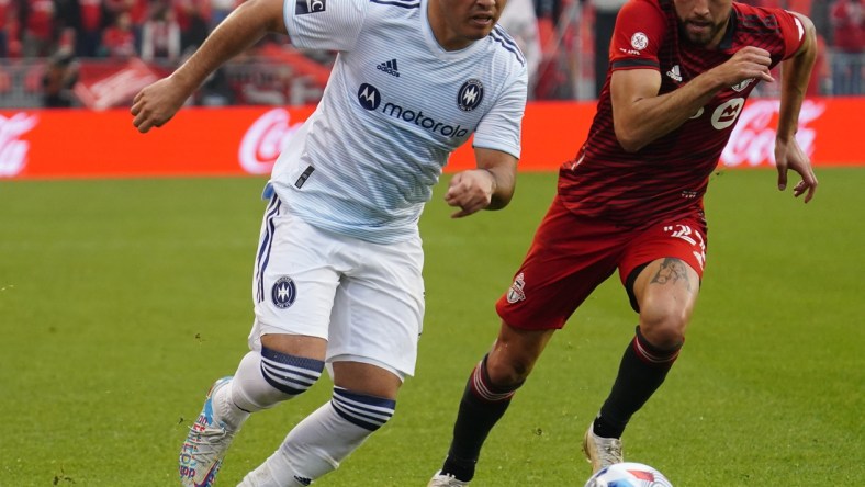 Oct 3, 2021; Toronto, Ontario, CAN; Chicago Fire forward Ignacio Aliseda (7) gets by Toronto FC midfielder Jonathan Osorio (21) during the second half at BMO Field. Mandatory Credit: John E. Sokolowski-USA TODAY Sports