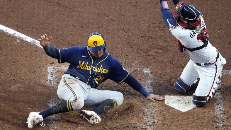 Oct 12, 2021; Cumberland, Georgia, USA; Milwaukee Brewers right fielder Avisail Garcia (left) scores a run ahead of the throw to Atlanta Braves catcher Travis d'Arnaud (16) on a single hit by catcher Omar Narvaez (not pictured) during the fourth inning during game four of the 2021 ALDS at Truist Park. Mandatory Credit: Dale Zanine-USA TODAY Sports