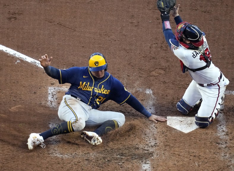 Oct 12, 2021; Cumberland, Georgia, USA; Milwaukee Brewers right fielder Avisail Garcia (left) scores a run ahead of the throw to Atlanta Braves catcher Travis d'Arnaud (16) on a single hit by catcher Omar Narvaez (not pictured) during the fourth inning during game four of the 2021 ALDS at Truist Park. Mandatory Credit: Dale Zanine-USA TODAY Sports