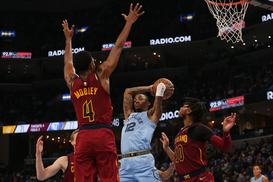 Oct 20, 2021; Memphis, Tennessee, USA; Memphis Grizzles guard Ja Morant (12) passes the ball as Cleveland Cavaliers center Evan Mobley (4) and  guard Darius Garland (10) defend during the second half at FedExForum. Mandatory Credit: Petre Thomas-USA TODAY Sports