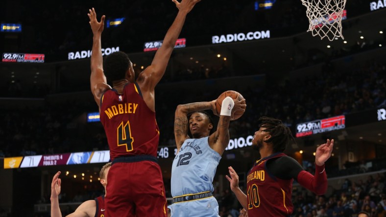 Oct 20, 2021; Memphis, Tennessee, USA; Memphis Grizzles guard Ja Morant (12) passes the ball as Cleveland Cavaliers center Evan Mobley (4) and  guard Darius Garland (10) defend during the second half at FedExForum. Mandatory Credit: Petre Thomas-USA TODAY Sports