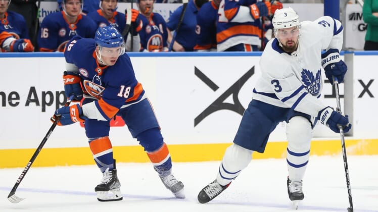 Nov 21, 2021; Elmont, New York, USA;  Toronto Maple Leafs defenseman Justin Holl (3) skates the puck past New York Islanders left wing Anthony Beauvillier (18)  at UBS Arena. Mandatory Credit: Tom Horak-USA TODAY Sports