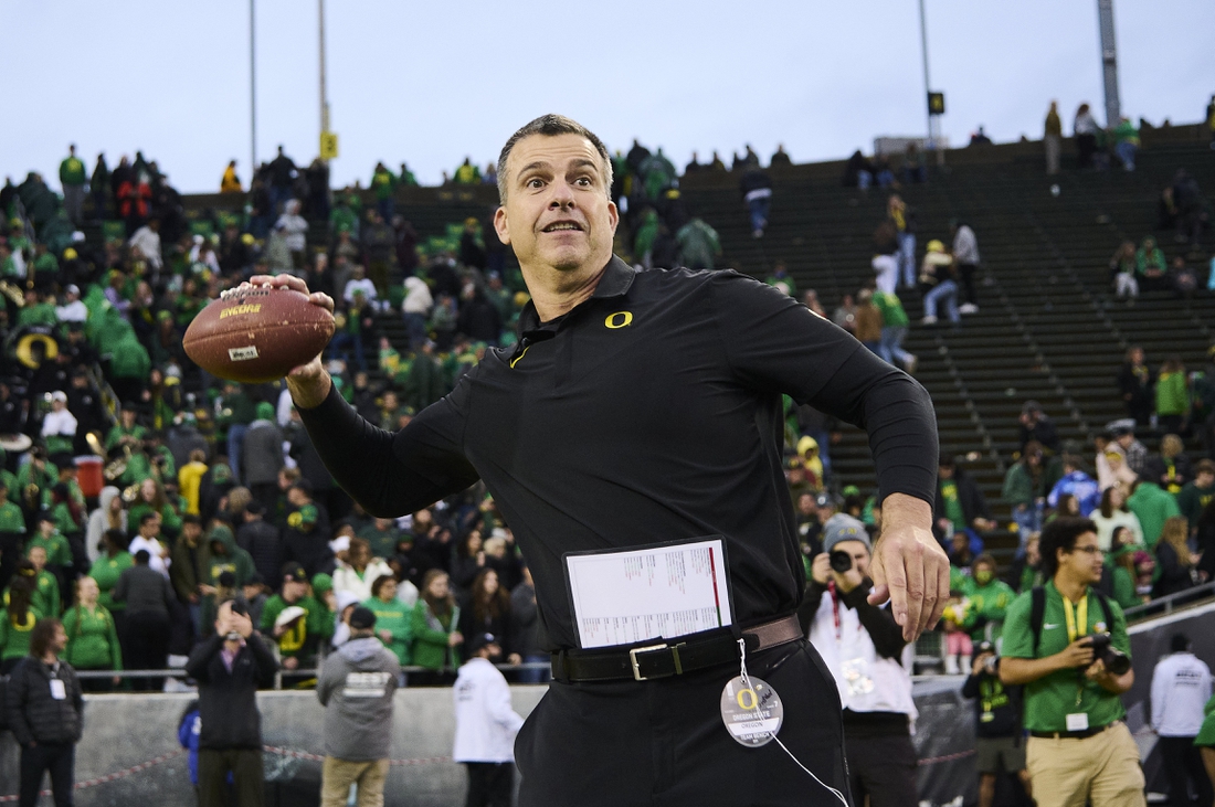 Nov 27, 2021; Eugene, Oregon, USA; Oregon Ducks head coach Mario Cristobal throws a football to his son   s after a game against the Oregon State Beavers at Autzen Stadium. The Ducks won 38-29. Mandatory Credit: Troy Wayrynen-USA TODAY Sports