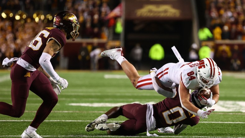 Nov 27, 2021; Minneapolis, Minnesota, USA; Wisconsin Badgers tight end Jake Ferguson (84) runs the ball as Minnesota Gophers defensive back Justin Walley (0) tackles him during the fourth quarter  at Huntington Bank Stadium. Mandatory Credit: Harrison Barden-USA TODAY Sports