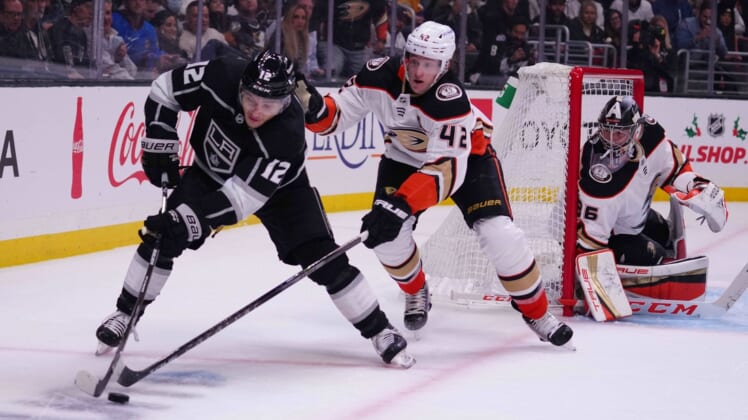 Nov 30, 2021; Los Angeles, California, USA; LA Kings center Trevor Moore (12) and Anaheim Ducks defenseman Josh Manson (42) battle for the puck as Ducks goaltender John Gibson (36) watches in the second period at Staples Center. Mandatory Credit: Kirby Lee-USA TODAY Sports