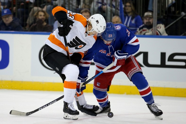Dec 1, 2021; New York, New York, USA; Philadelphia Flyers left wing Oskar Lindblom (23) and New York Rangers defenseman Adam Fox (23) fight for the puck during the first period at Madison Square Garden. Mandatory Credit: Brad Penner-USA TODAY Sports