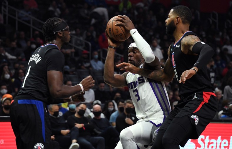 Dec 1, 2021; Los Angeles, California, USA; Sacramento Kings forward Terence Davis (3) drives to the basket while defended by Los Angeles Clippers guard Reggie Jackson (1) and forward Marcus Morris (8) during the third quarter at Staples Center. Mandatory Credit: Richard Mackson-USA TODAY Sports