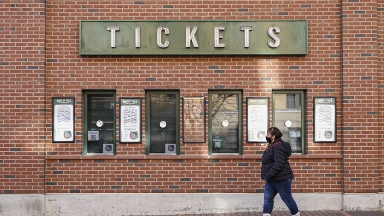 Dec 2, 2021; Chicago, IL, USA; A woman walks by locked Wrigley Field on the first day of Major League Baseball lockout. Mandatory Credit: Kamil Krzaczynski-USA TODAY Sports