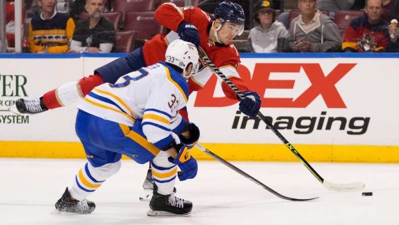 Dec 2, 2021; Sunrise, Florida, USA; Florida Panthers left wing Frank Vatrano (77) shoots the puck in front of Buffalo Sabres defenseman Colin Miller (33) during the second period at FLA Live Arena. Mandatory Credit: Jasen Vinlove-USA TODAY Sports