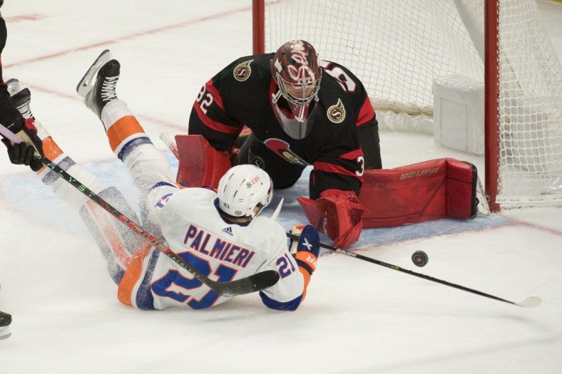 Dec 7, 2021; Ottawa, Ontario, CAN; New York Islanders center Kyle Palmieri (21) is knocked down as he shoots on Ottawa Senators goalie Filip Gustavsson (32) in the third period at the Canadian Tire Centre. Mandatory Credit: Marc DesRosiers-USA TODAY Sports