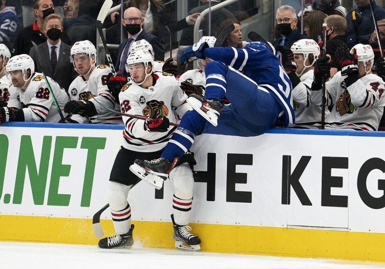 Dec 11, 2021; Toronto, Ontario, CAN; Chicago Blackhawks center Reese Johnson (52) battles along the boards with Toronto Maple Leafs defenseman Kristians Rubins (56) during the second period at Scotiabank Arena. Mandatory Credit: Nick Turchiaro-USA TODAY Sports