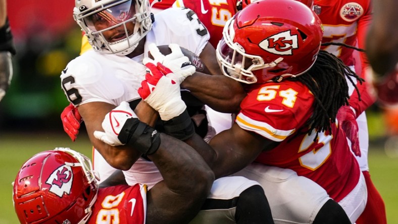 Dec 12, 2021; Kansas City, Missouri, USA; Las Vegas Raiders running back Trey Ragas (36) is tackled by Kansas City Chiefs defensive tackle Jarran Reed (90) and outside linebacker Nick Bolton (54) and safety Daniel Sorensen (49) during the second half at GEHA Field at Arrowhead Stadium. Mandatory Credit: Jay Biggerstaff-USA TODAY Sports