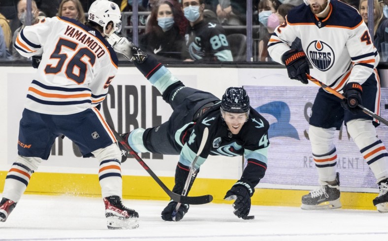 Dec 18, 2021; Seattle, Washington, USA; Seattle Kraken defenseman Haydn Fleury (4) goes to the ice while going for the puck against Edmonton Oilers right wing Kailer Yamamoto (56) during the first period at Climate Pledge Arena. Mandatory Credit: Stephen Brashear-USA TODAY Sports