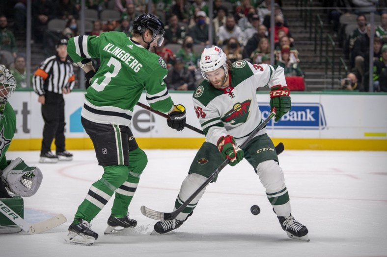 Dec 20, 2021; Dallas, Texas, USA; Dallas Stars defenseman John Klingberg (3) and Minnesota Wild right wing Ryan Hartman (38) battle for the puck during the first period at the American Airlines Center. Mandatory Credit: Jerome Miron-USA TODAY Sports