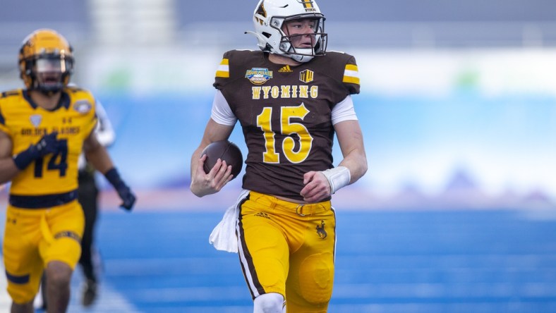 Dec 21, 2021; Boise, Idaho, USA; Wyoming Cowboys quarterback Levi Williams (15) runs the ball for a touchdown during the first half against the Kent State Golden Flashes during the 2021 Famous Idaho Potato Bowl at Albertsons Stadium. Mandatory Credit: Brian Losness-USA TODAY Sports