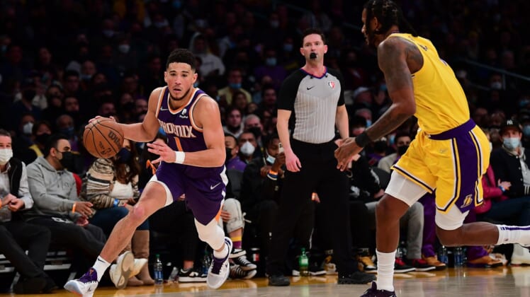 Dec 21, 2021; Los Angeles, California, USA; Phoenix Suns guard Devin Booker (1) moves to the basket against Los Angeles Lakers forward Trevor Ariza (1) during the second half at Staples Center. Mandatory Credit: Gary A. Vasquez-USA TODAY Sports