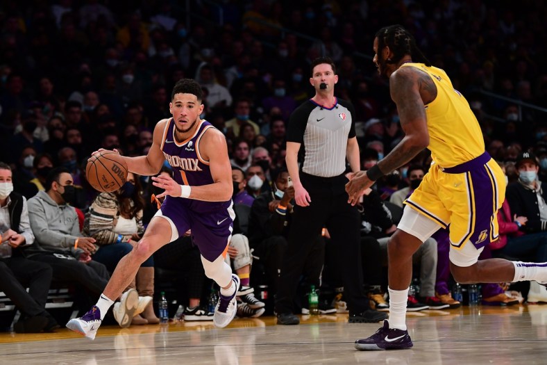 Dec 21, 2021; Los Angeles, California, USA; Phoenix Suns guard Devin Booker (1) moves to the basket against Los Angeles Lakers forward Trevor Ariza (1) during the second half at Staples Center. Mandatory Credit: Gary A. Vasquez-USA TODAY Sports