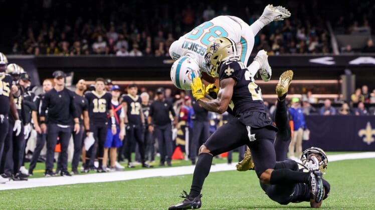 Dec 27, 2021; New Orleans, Louisiana, USA; Miami Dolphins tight end Mike Gesicki (88) leaps over New Orleans Saints cornerback Paulson Adebo (right) during the first half at Caesars Superdome. Mandatory Credit: Stephen Lew-USA TODAY Sports