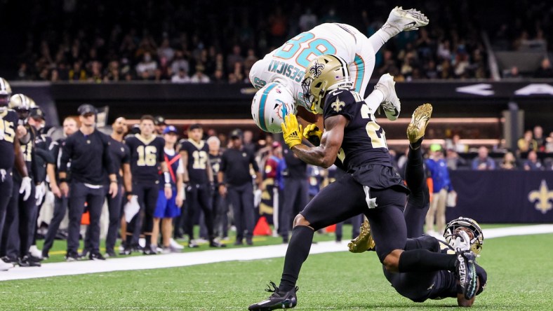 Dec 27, 2021; New Orleans, Louisiana, USA; Miami Dolphins tight end Mike Gesicki (88) leaps over New Orleans Saints cornerback Paulson Adebo (right) during the first half at Caesars Superdome. Mandatory Credit: Stephen Lew-USA TODAY Sports