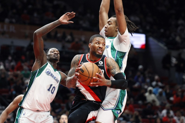 Dec 27, 2021; Portland, Oregon, USA; Portland Trail Blazers point guard Damian Lillard (0) looks to pass while defended by Dallas Mavericks center Moses Brown (9, right) during the first half at Moda Center. Mandatory Credit: Soobum Im-USA TODAY Sports