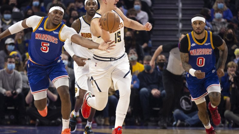 Dec 28, 2021; San Francisco, California, USA; Golden State Warriors forward Kevon Looney (5) tries to steal the ball from Denver Nuggets center Nikola Jokic (15) during the first quarter at Chase Center. Mandatory Credit: D. Ross Cameron-USA TODAY Sports