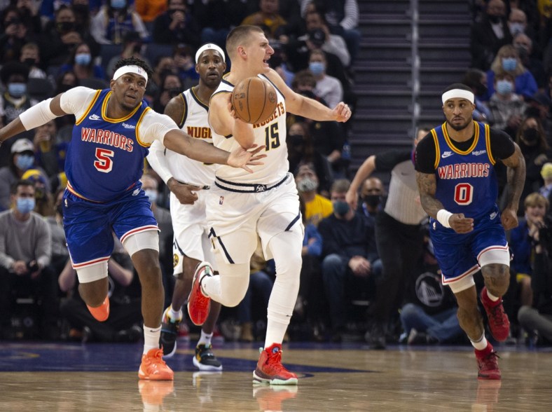 Dec 28, 2021; San Francisco, California, USA; Golden State Warriors forward Kevon Looney (5) tries to steal the ball from Denver Nuggets center Nikola Jokic (15) during the first quarter at Chase Center. Mandatory Credit: D. Ross Cameron-USA TODAY Sports