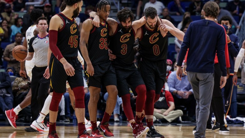 Dec 28, 2021; New Orleans, Louisiana, USA; Cleveland Cavaliers guard Ricky Rubio (3) is helped off the court by forward Kevin Love (0) and forward Isaac Okoro (35) after injuring his ankle against New Orleans Pelicans forward Herbert Jones (5) during the second half at Smoothie King Center. Mandatory Credit: Stephen Lew-USA TODAY Sports