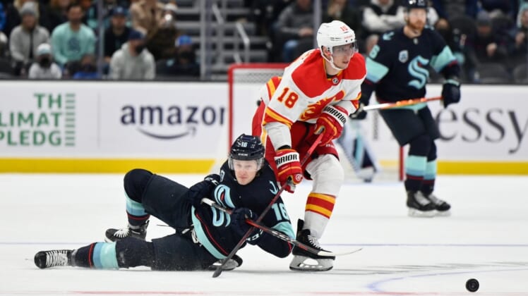 Dec 30, 2021; Seattle, Washington, USA; Seattle Kraken left wing Jared McCann (16) and Calgary Flames center Tyler Pitlick (18) fight for the puck during the first period at Climate Pledge Arena. Mandatory Credit: Steven Bisig-USA TODAY Sports