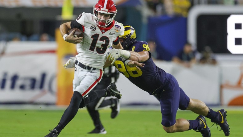 Dec 31, 2021; Miami Gardens, Florida, USA; Georgia Bulldogs quarterback Stetson Bennett (13) runs with the ball ahead of Michigan Wolverines defensive lineman Julius Welschof (96) in the second quarter during the Orange Bowl college football CFP national semifinal game at Hard Rock Stadium. Mandatory Credit: Sam Navarro-USA TODAY Sports