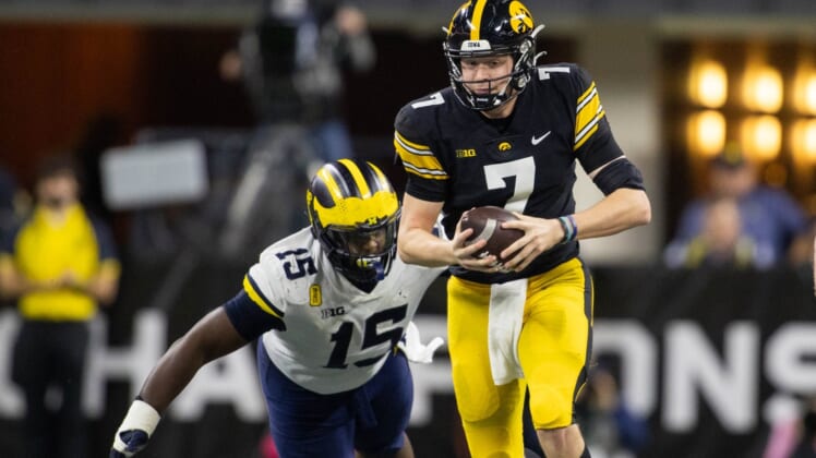 Dec 4, 2021; Indianapolis, IN, USA;  Iowa Hawkeyes quarterback Spencer Petras (7) runs the ball while *Michigan Wolverines defensive lineman Christopher Hinton (15) defends in the second quarter at Lucas Oil Stadium. Mandatory Credit: Trevor Ruszkowski-USA TODAY Sports