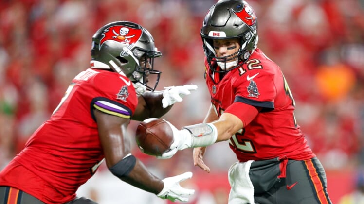 Dec 19, 2021; Tampa, Florida, USA;  Tampa Bay Buccaneers quarterback Tom Brady (12) hands off to running back Leonard Fournette (7) in the second quarter against the New Orleans Saints at Raymond James Stadium. Mandatory Credit: Nathan Ray Seebeck-USA TODAY Sports