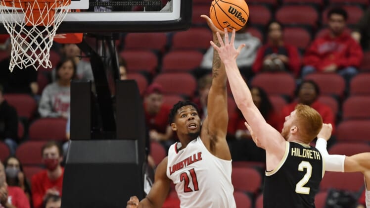 Dec 29, 2021; Louisville, Kentucky, USA;  Louisville Cardinals forward Sydney Curry (21) challenges the shot of Wake Forest Demon Deacons guard Cameron Hildreth (2) during the second half at KFC Yum! Center. Louisville defeated Wake Forest 73-69. Mandatory Credit: Jamie Rhodes-USA TODAY Sports
