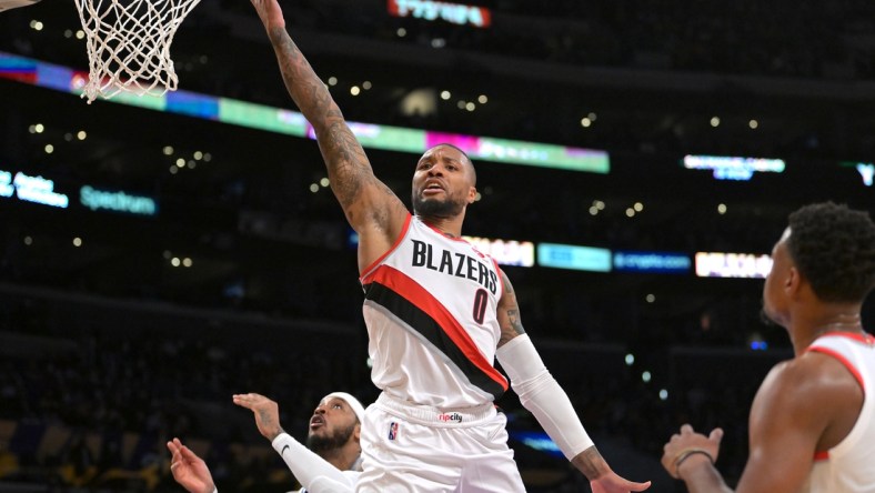 Dec 31, 2021; Los Angeles, California, USA; Portland Trail Blazers guard Damian Lillard (0) goes to the basket past Los Angeles Lakers forward Carmelo Anthony (7) in the first half at Crypto.com Arena. Mandatory Credit: Jayne Kamin-Oncea-USA TODAY Sports