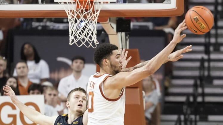 Jan 1, 2022; Austin, Texas, USA; Texas Longhorns forward Timmy Allen (0) passes the ball while defended by shoots over West Virginia Mountaineers guard Sean McNeil (22) during the second half at Frank C. Erwin Jr. Center. Mandatory Credit: Scott Wachter-USA TODAY Sports