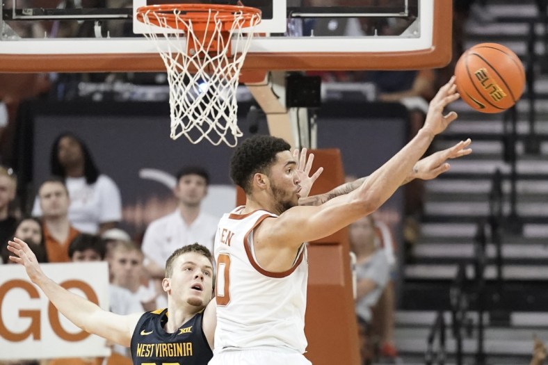 Jan 1, 2022; Austin, Texas, USA; Texas Longhorns forward Timmy Allen (0) passes the ball while defended by shoots over West Virginia Mountaineers guard Sean McNeil (22) during the second half at Frank C. Erwin Jr. Center. Mandatory Credit: Scott Wachter-USA TODAY Sports