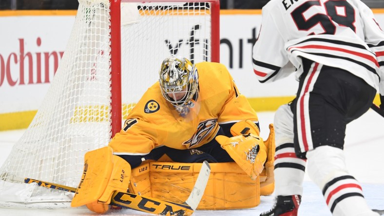 Jan 1, 2022; Nashville, Tennessee, USA; Nashville Predators goaltender Juuse Saros (74) makes a save on a shot by Chicago Blackhawks right wing MacKenzie Entwistle (58) during the second period at Bridgestone Arena. Mandatory Credit: Christopher Hanewinckel-USA TODAY Sports