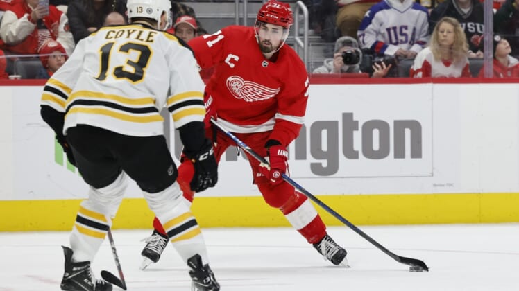 Jan 2, 2022; Detroit, Michigan, USA;  Detroit Red Wings center Dylan Larkin (71) skates with the puck defended by Boston Bruins center Charlie Coyle (13) in the second period at Little Caesars Arena. Mandatory Credit: Rick Osentoski-USA TODAY Sports