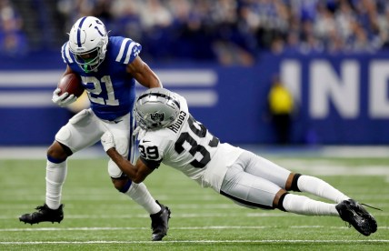 Indianapolis Colts running back Nyheim Hines (21) pushes off of Las Vegas Raiders cornerback Nate Hobbs (39) while rushing the ball Sunday, Jan. 2, 2022, during a game at Lucas Oil Stadium in Indianapolis.