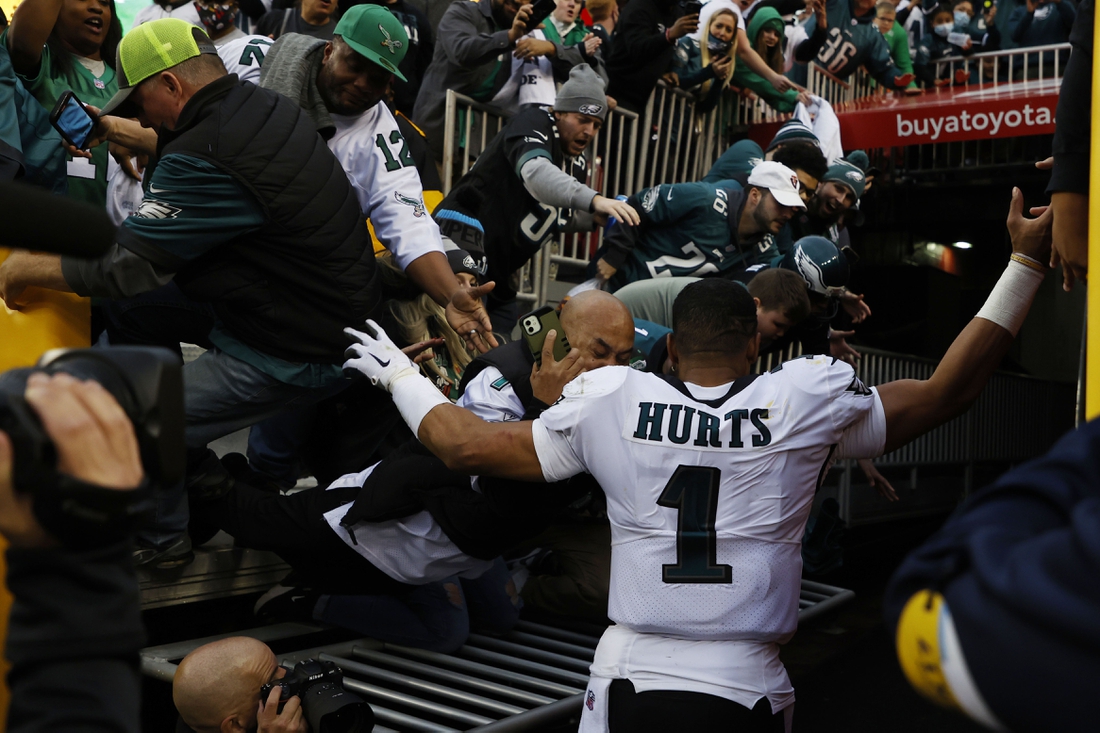 Jan 2, 2022; Landover, Maryland, USA; Fans fall from the stands after a railing gives way as Philadelphia Eagles quarterback Jalen Hurts (1) leaves the field after the Eagles' game against the Washington Football Team at FedExField. Mandatory Credit: Geoff Burke-USA TODAY Sports