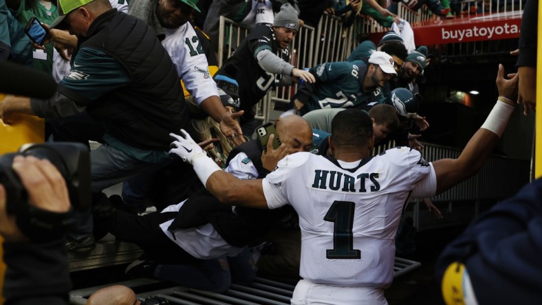 Jan 2, 2022; Landover, Maryland, USA; Fans fall from the stands after a railing gives way as Philadelphia Eagles quarterback Jalen Hurts (1) leaves the field after the Eagles' game against the Washington Football Team at FedExField. Mandatory Credit: Geoff Burke-USA TODAY Sports