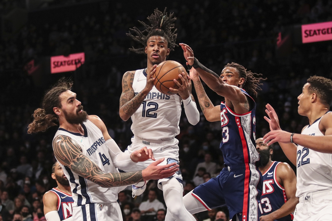 Jan 3, 2022; Brooklyn, New York, USA;  Memphis Grizzlies guard Ja Morant (12) drives in between center Steven Adams (4) and Brooklyn Nets forward Nic Claxton (33) for a layup attempt in the third quarter at Barclays Center. Mandatory Credit: Wendell Cruz-USA TODAY Sports