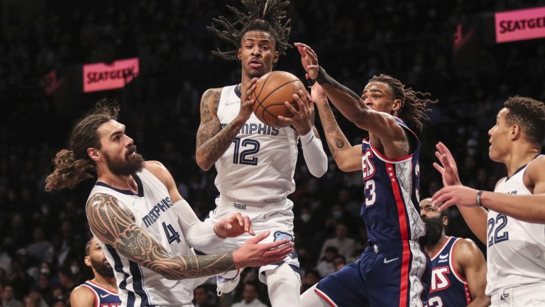 Jan 3, 2022; Brooklyn, New York, USA;  Memphis Grizzlies guard Ja Morant (12) drives in between center Steven Adams (4) and Brooklyn Nets forward Nic Claxton (33) for a layup attempt in the third quarter at Barclays Center. Mandatory Credit: Wendell Cruz-USA TODAY Sports