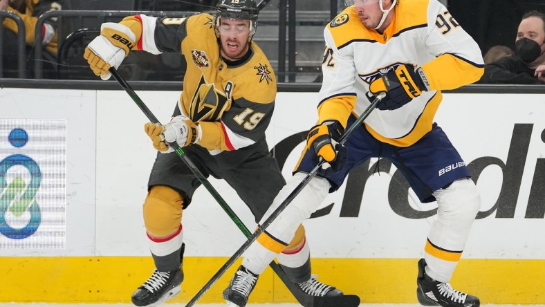 Jan 4, 2022; Las Vegas, Nevada, USA; Nashville Predators center Ryan Johansen (92) chips the puck away from Vegas Golden Knights right wing Reilly Smith (19) during the first period at T-Mobile Arena. Mandatory Credit: Stephen R. Sylvanie-USA TODAY Sports