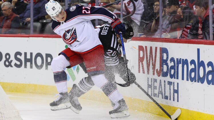 Jan 6, 2022; Newark, New Jersey, USA; Columbus Blue Jackets defenseman Adam Boqvist (27) and New Jersey Devils center Michael McLeod (20) battle for the puck during the second period at Prudential Center. Mandatory Credit: Ed Mulholland-USA TODAY Sports