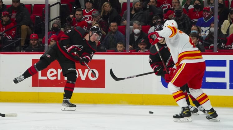 Jan 7, 2022; Raleigh, North Carolina, USA;  Carolina Hurricanes right wing Andrei Svechnikov (37) takes a shot past Calgary Flames defenseman Rasmus Andersson (4) during the first period at PNC Arena. Mandatory Credit: James Guillory-USA TODAY Sports